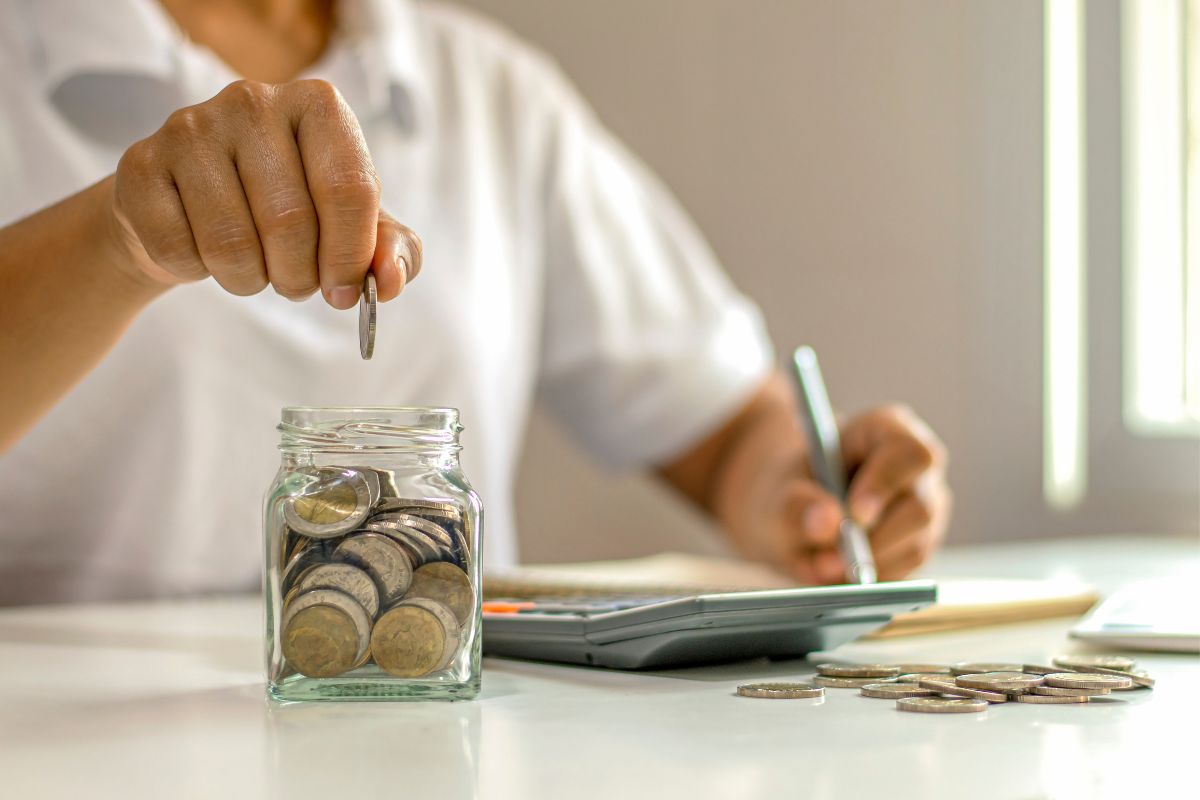 A picture of someone adding coins to a money jar.
