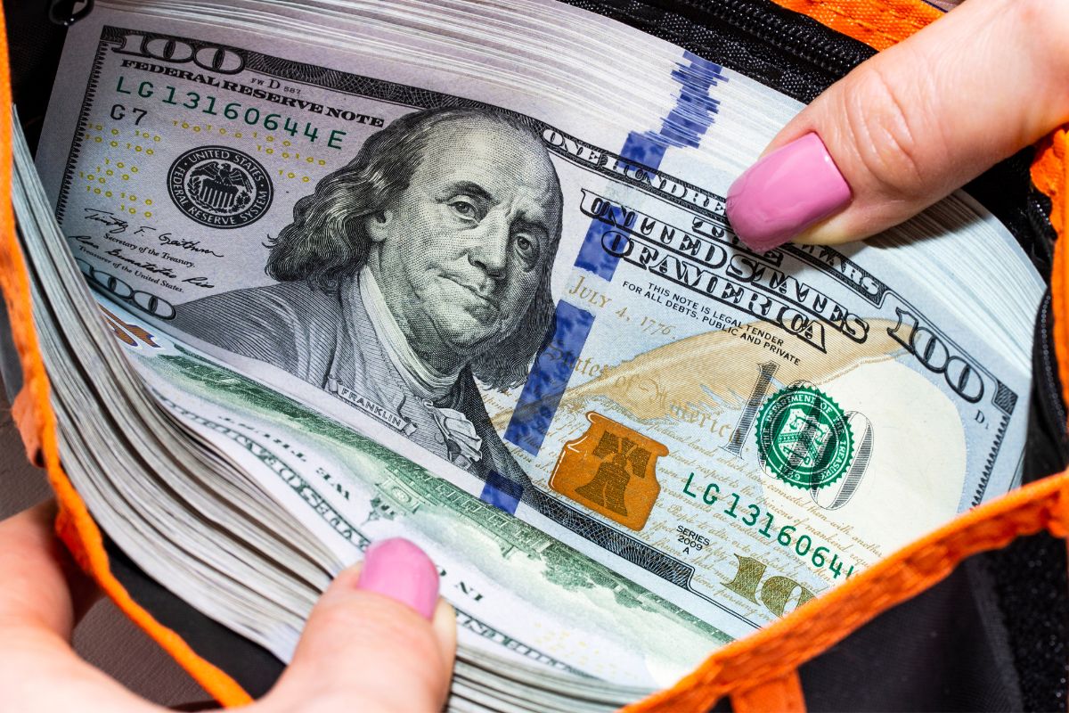 A picture of a wallet containing multiple $100s.