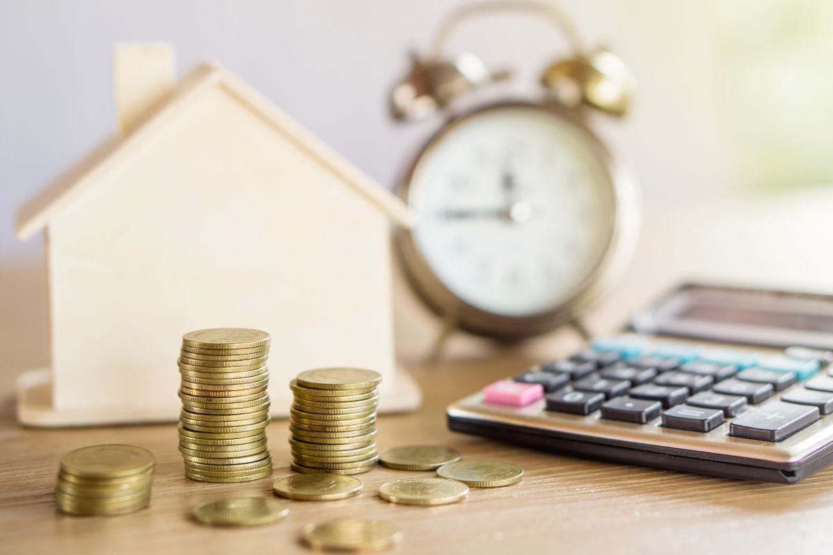 A picture of coins, house, calculator, and an alarm clock.