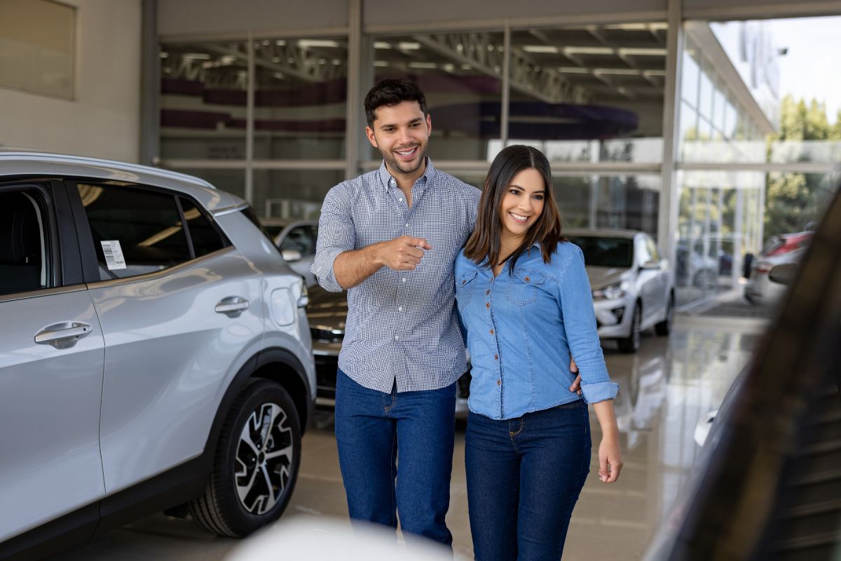 A picture of a couple looking at a car.