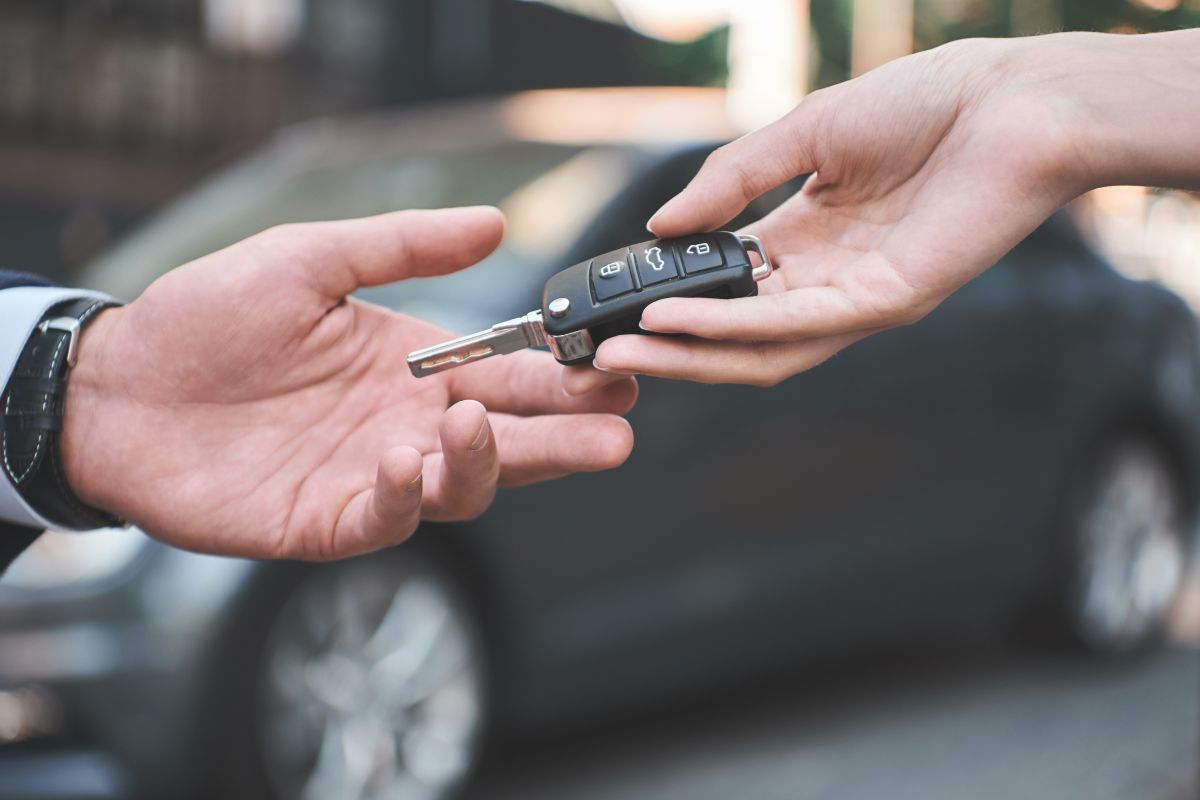 A picture of someone handling key car keys to another one.