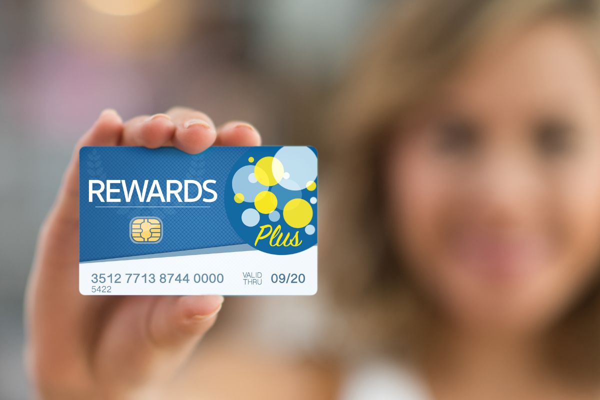A picture of a woman holding her credit rewards card..