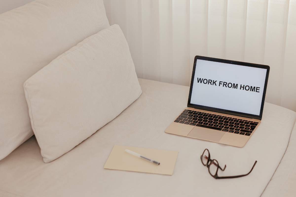 An image of a laptop, glasses, pen, and paper. 