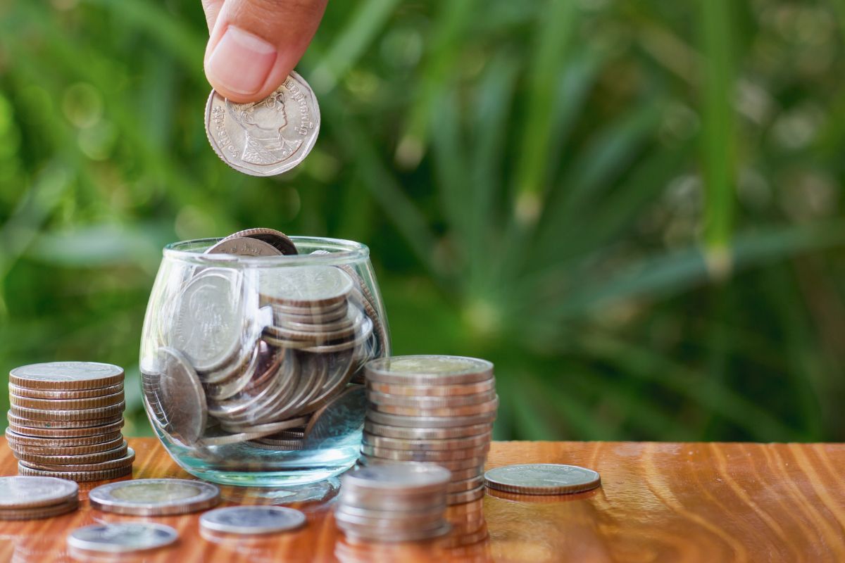 Picture of a finger putting dimes on a jar. 