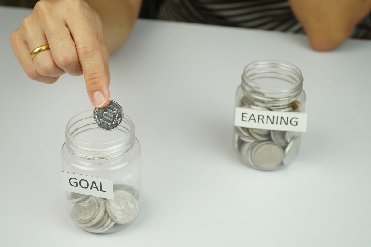 A picture of someone putting coins in her goal jar. 