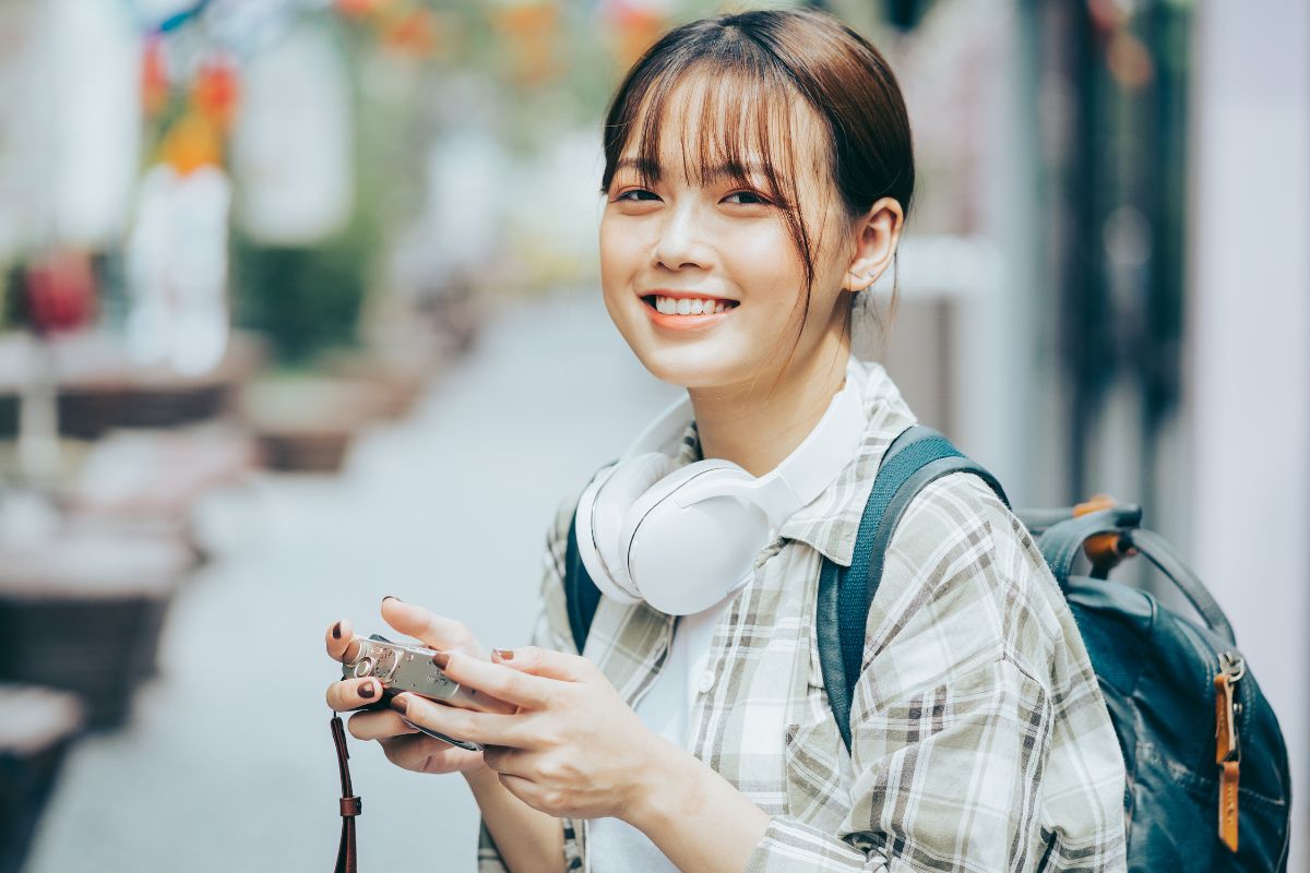 A picture of a woman with her camera and headphones. 