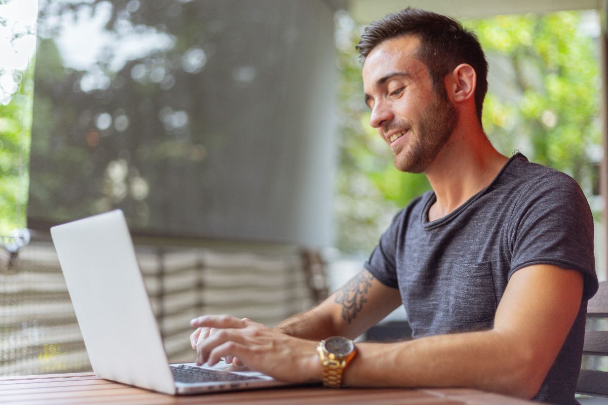 A picture of a man smiling with his laptop. 