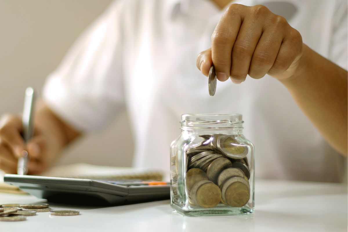A picture of someone putting a coin in a jar. 