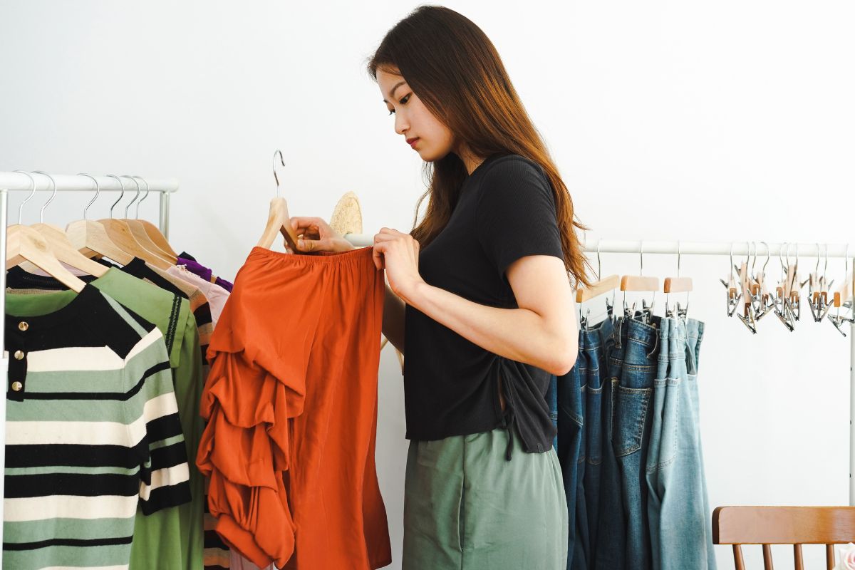 A picture of a lady looking at a dress. 