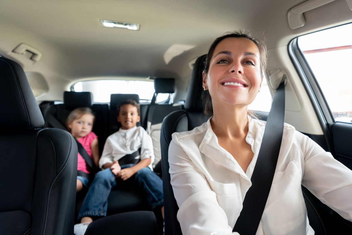 A picture of a mother and her children in the car.