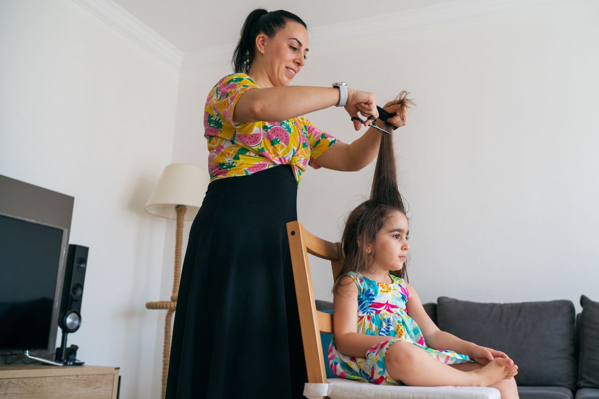 A picture of a mother cutting her daughter's hair.