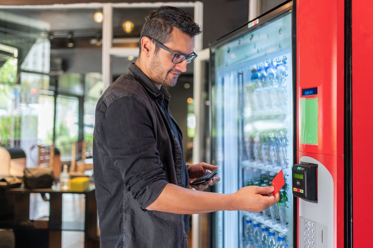 A picture of a man paying a vending machine.