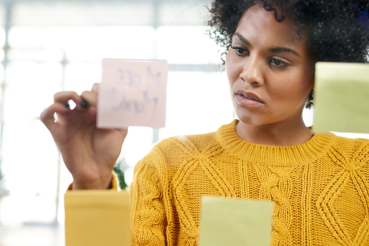 A picture of a lady putting a sticky note on a glass.