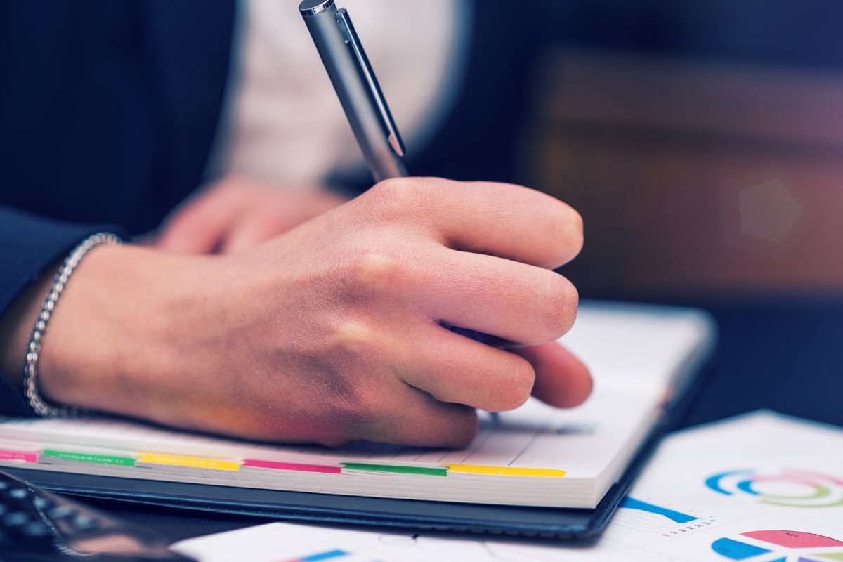A picture of someone writing in a planner. 