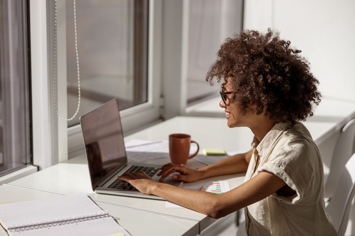 A picture of a lady smiling at her laptop. 
