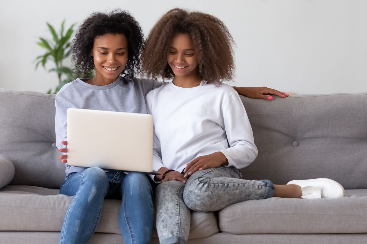 A picture of a mother and her daughter looking at her laptop.