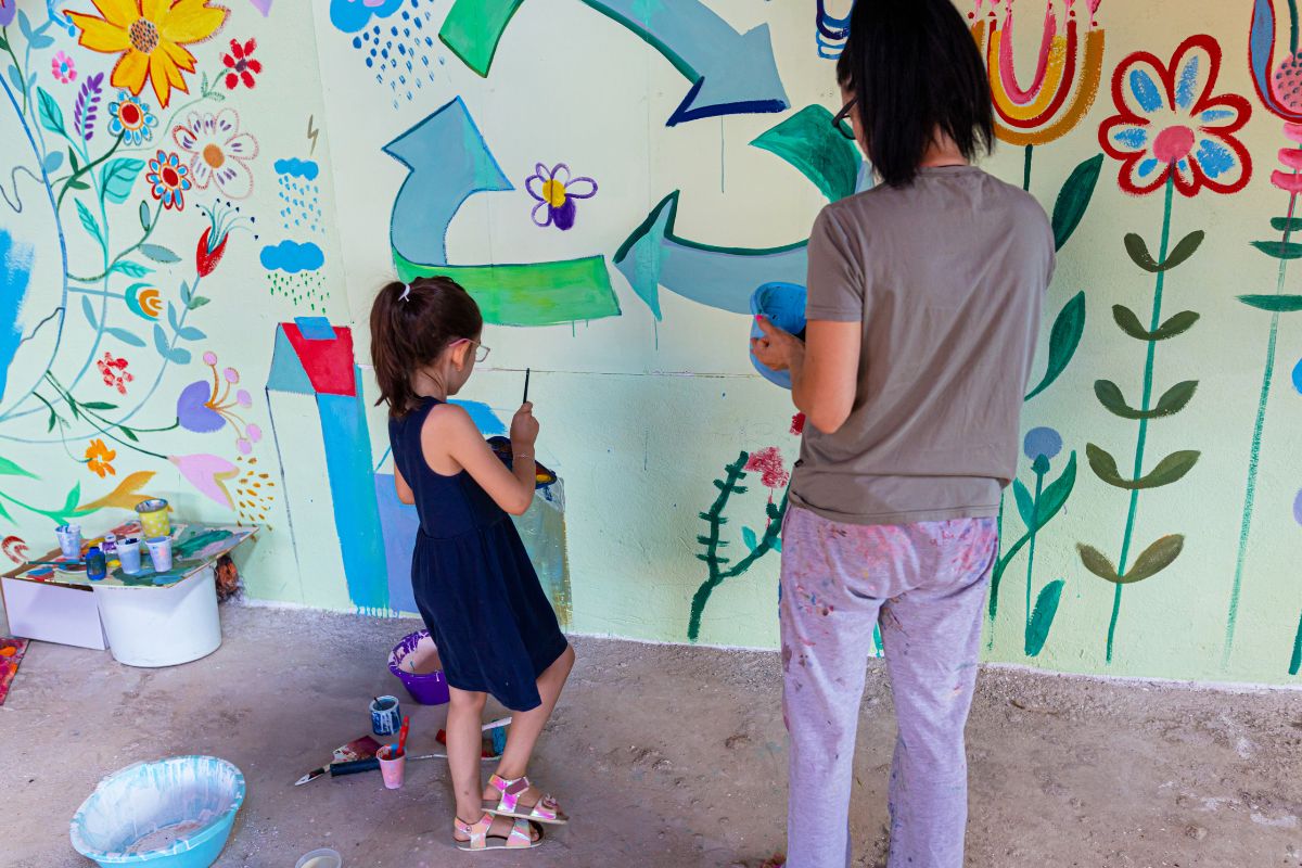 A picture of a mother and her daughter painting a wall. 