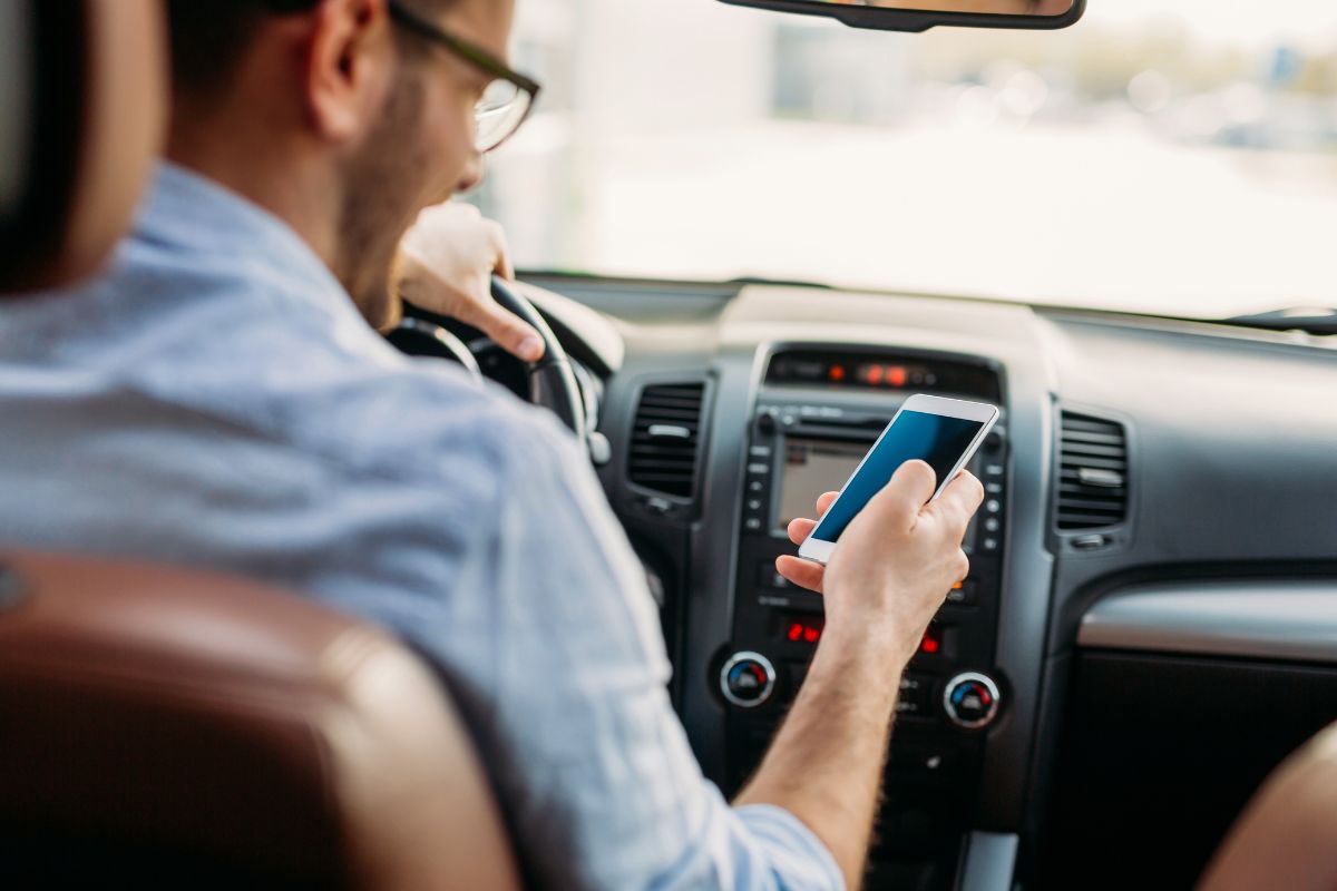 A picture of a man looking at his phone while driving.