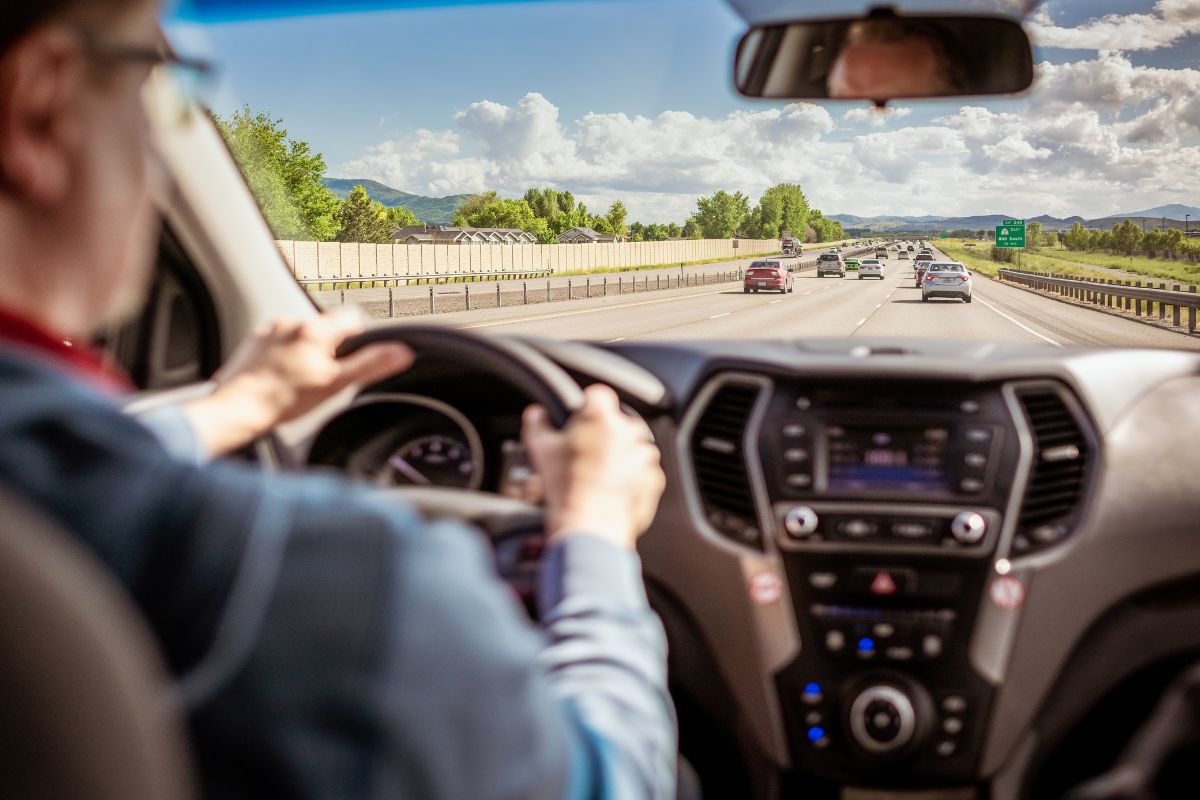 A picture of a man driving at a rural highway.