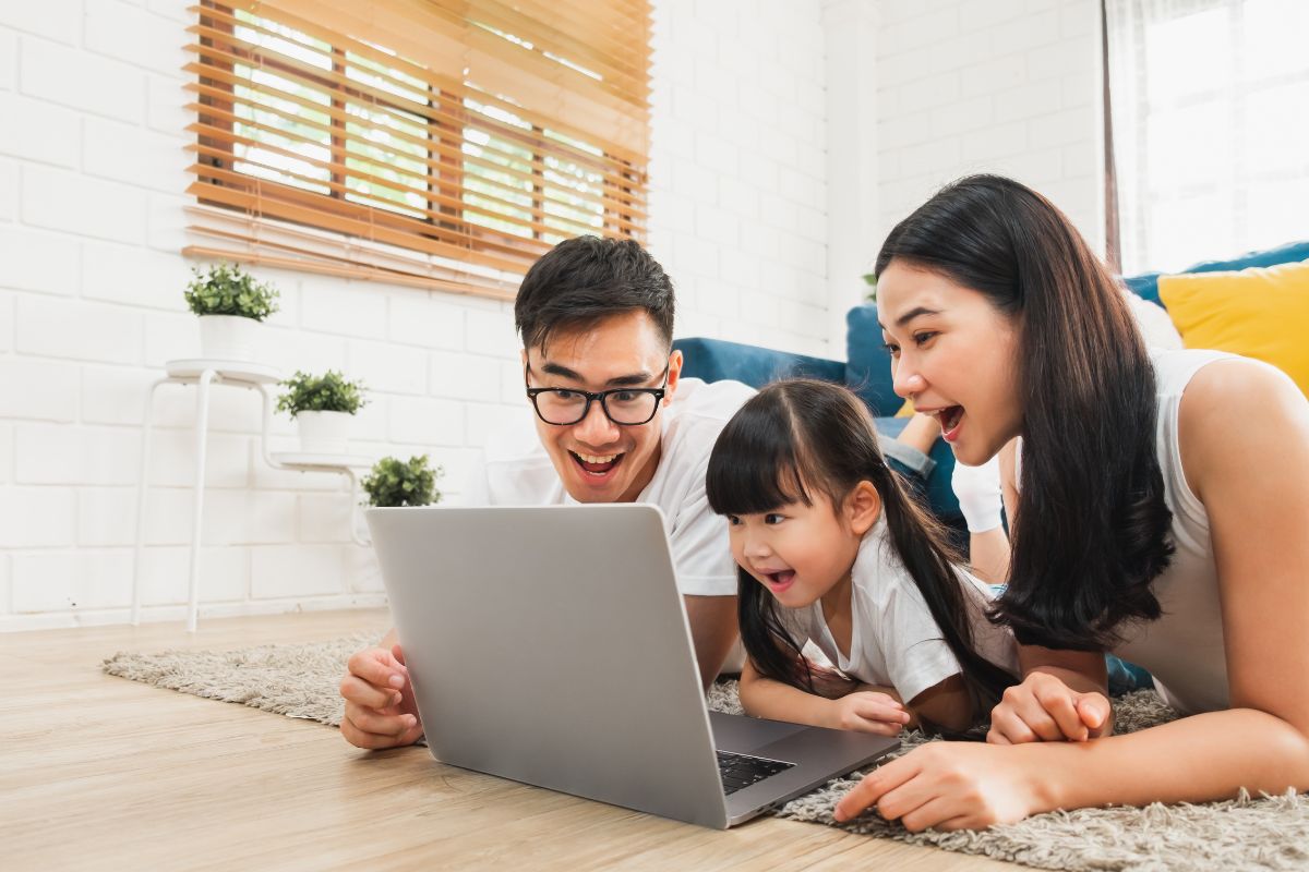 A picture of a family looking at a laptop, smiling. 