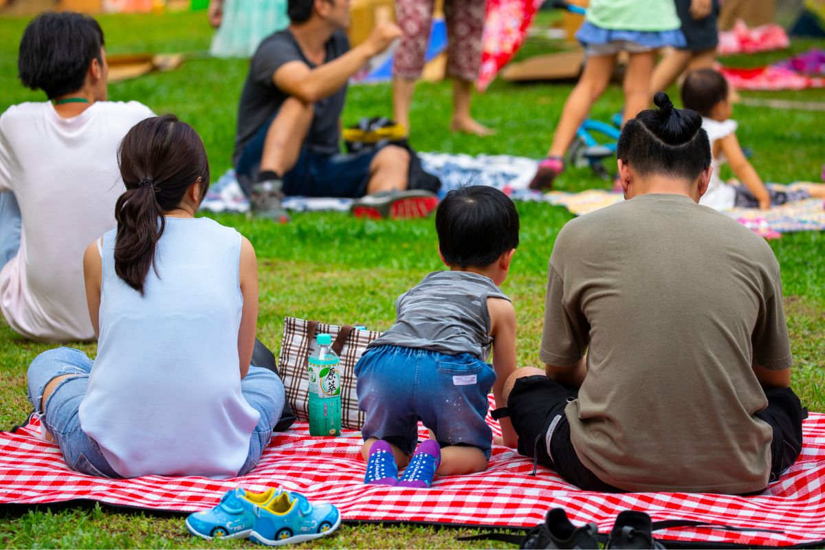 A picture of a family having a picnic at a public park. 