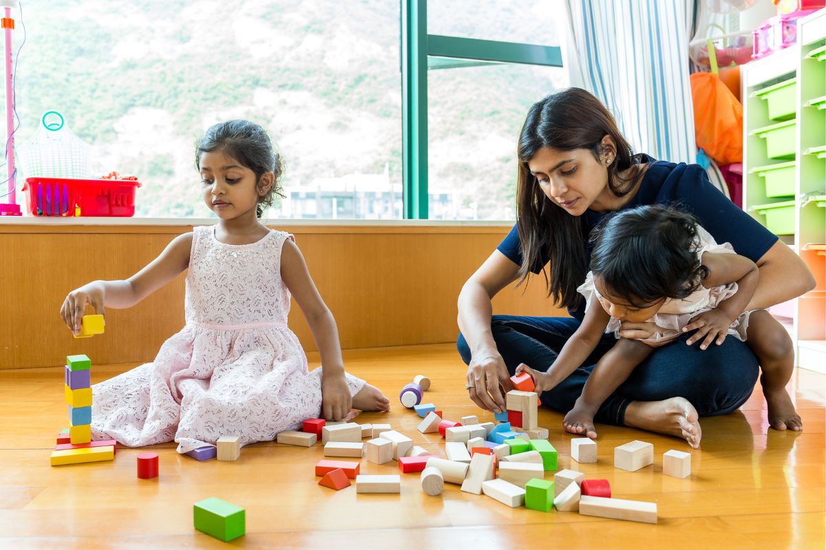 A picture of a mom and her kids playing blocks. 