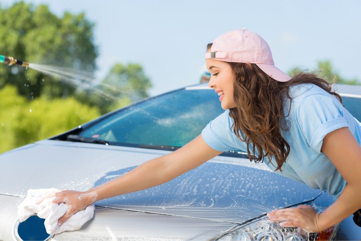 A picture of a lady washing a car.