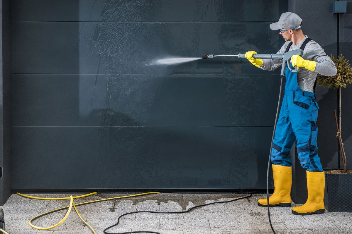 A picture of a man washing a garage door.