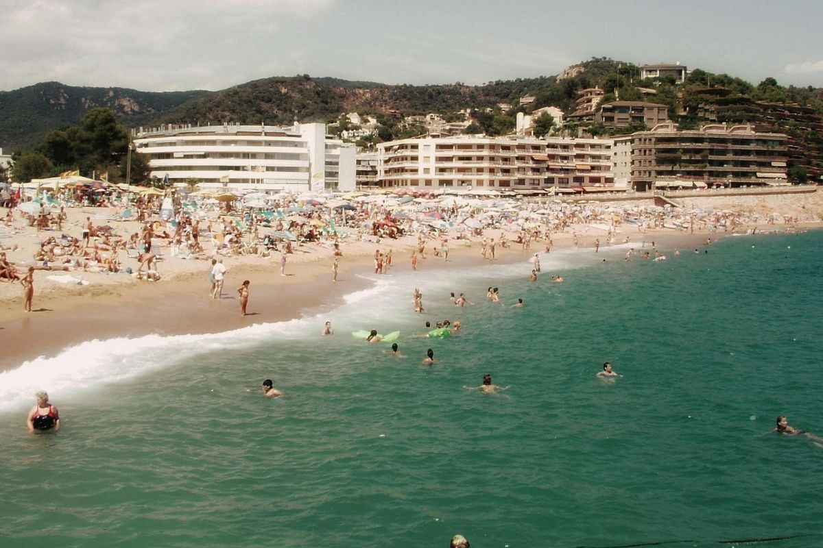 A picture of a beach with a lot of swimmers. 
