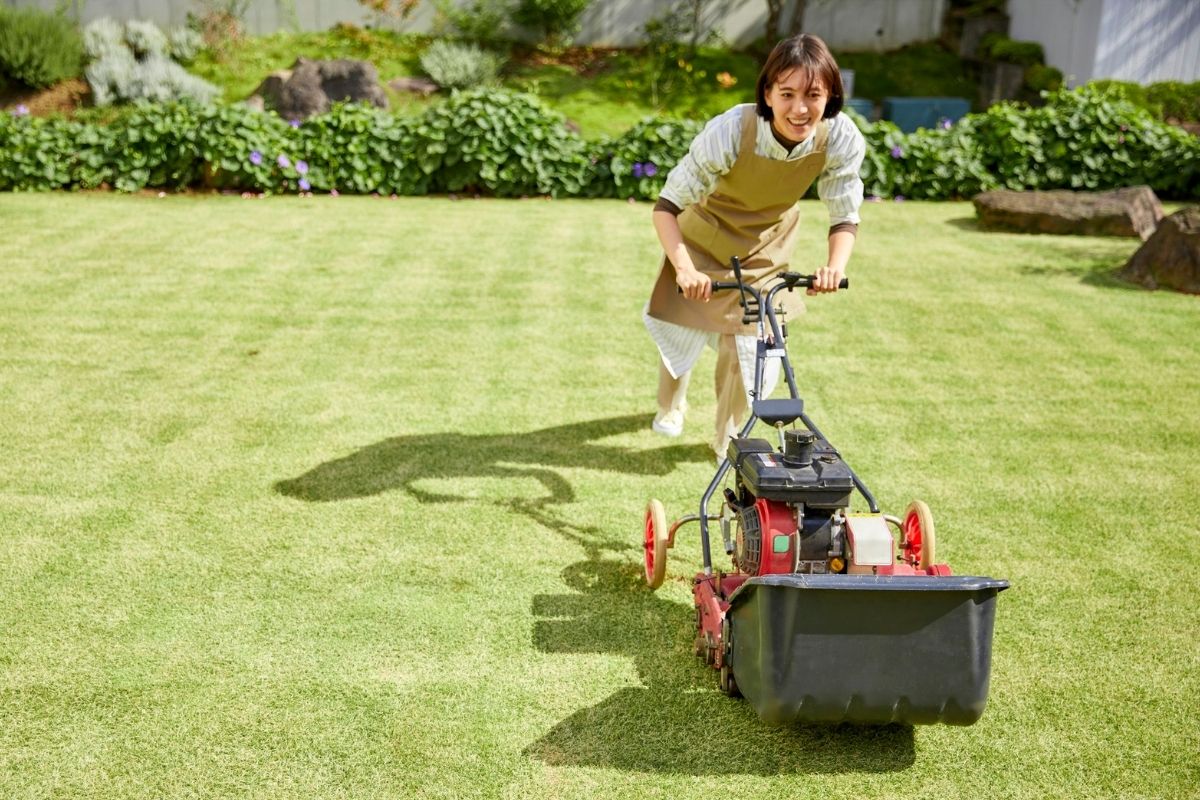 A picture of a lady lawn mowing .