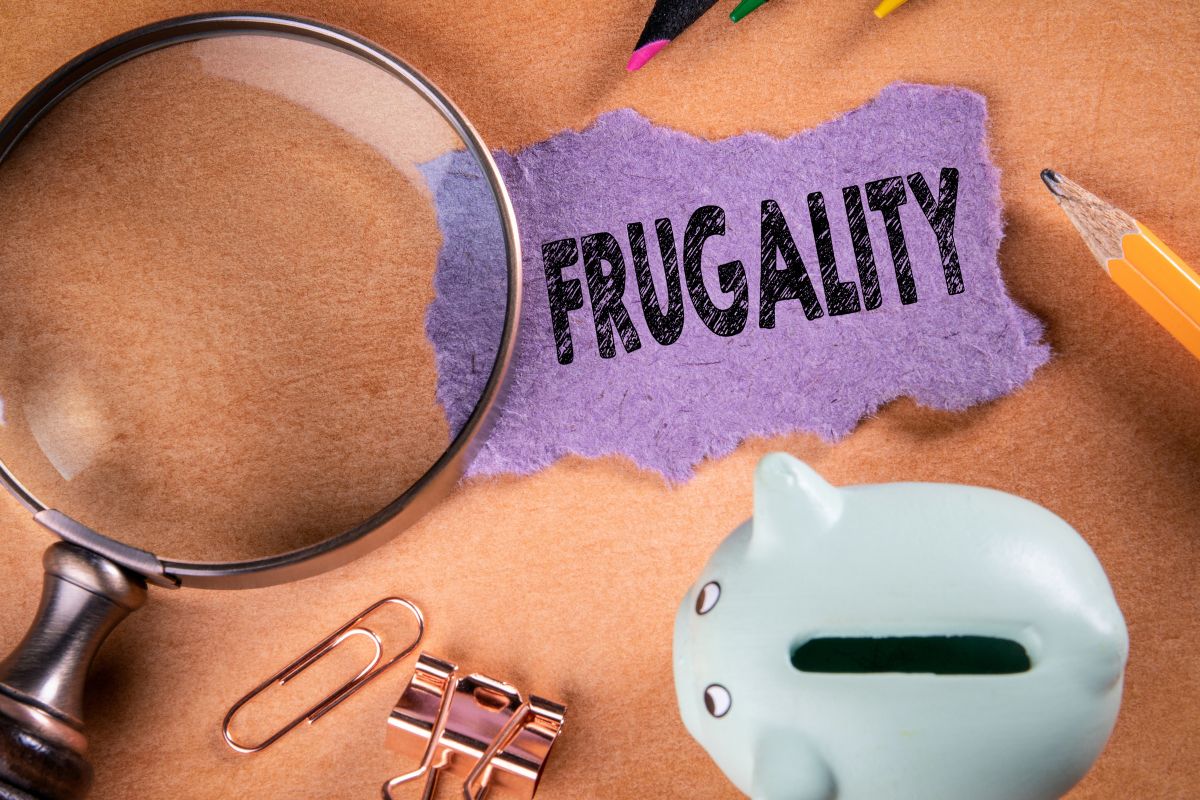 The photo shows a piggy bank and a paper with frugality wording.