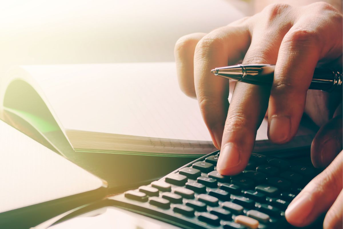The photo shows a lady's hand calculating a budget.