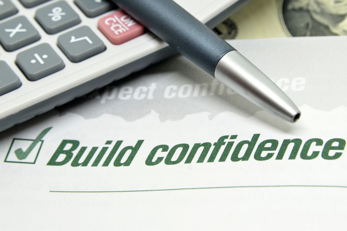 The photo shows a calculator and a paper with a build confidence note.