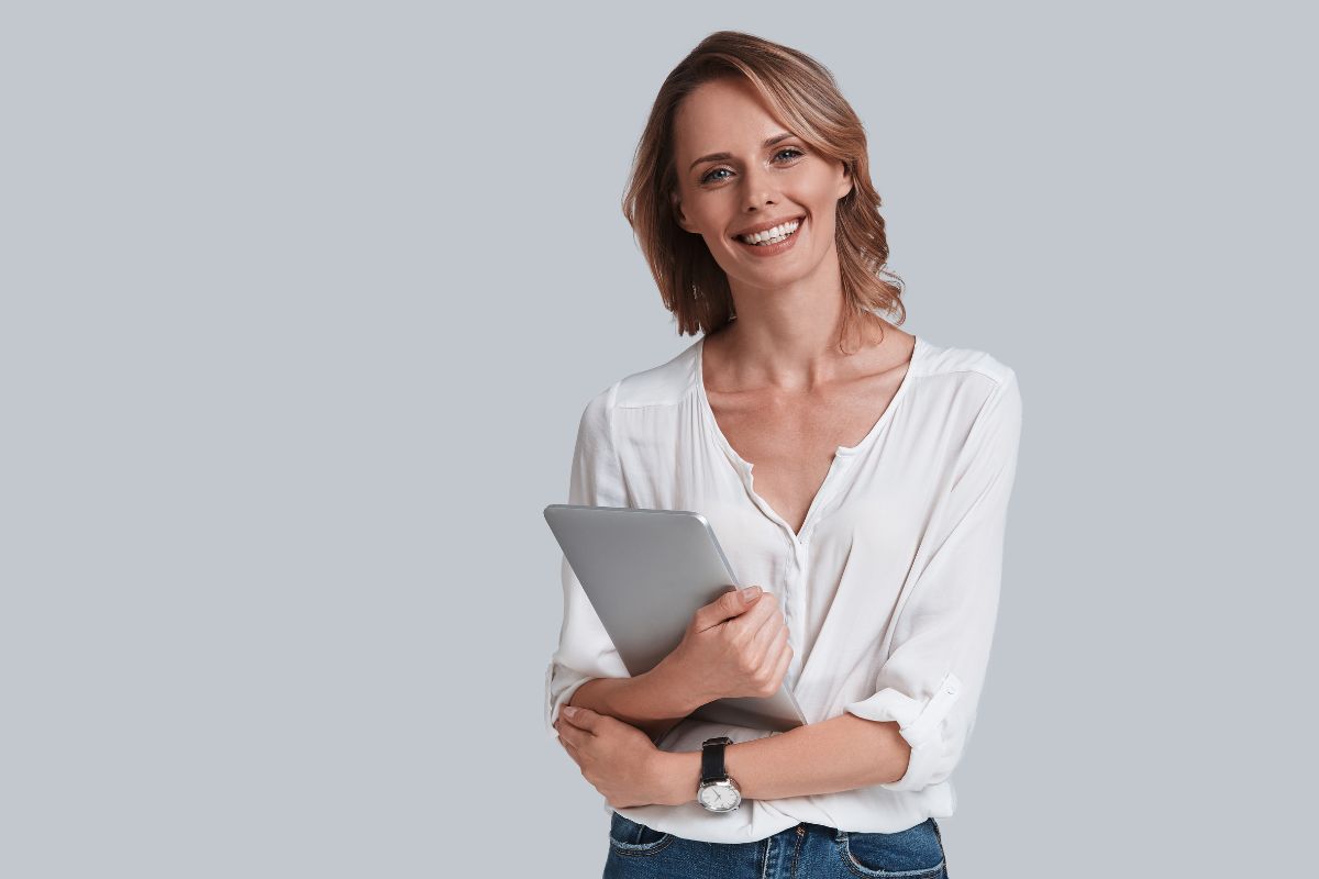 The image shows a girl smiling while holding a tablet device.
