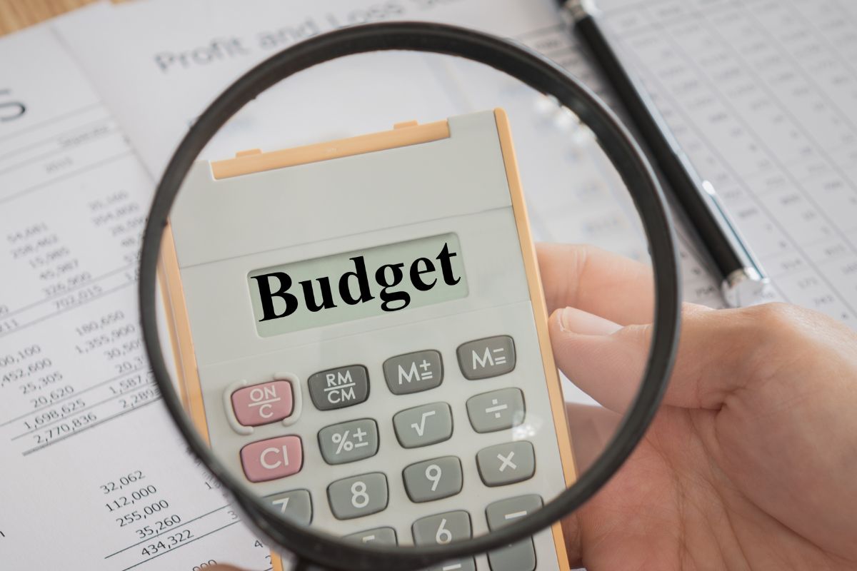 The image is about papers and a man's hand doing a bare bones budget.
