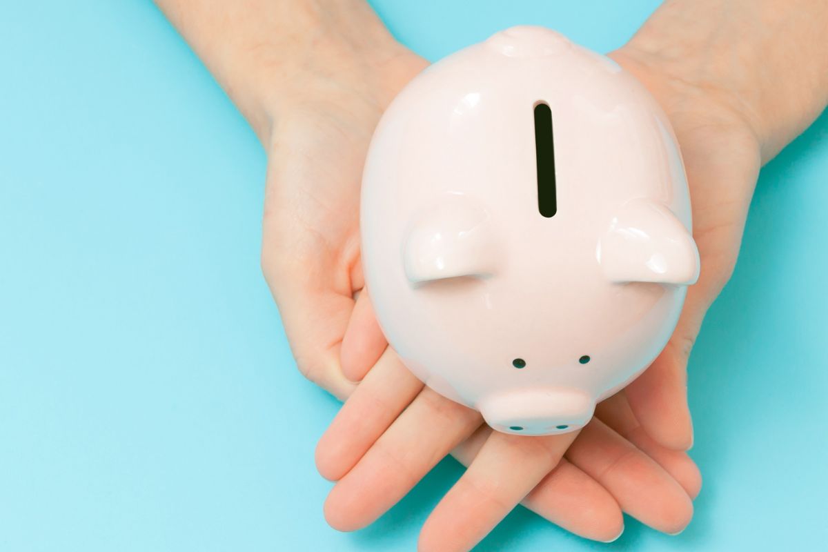 The photo is about a lady's hand holding a piggy bank for mini savings.