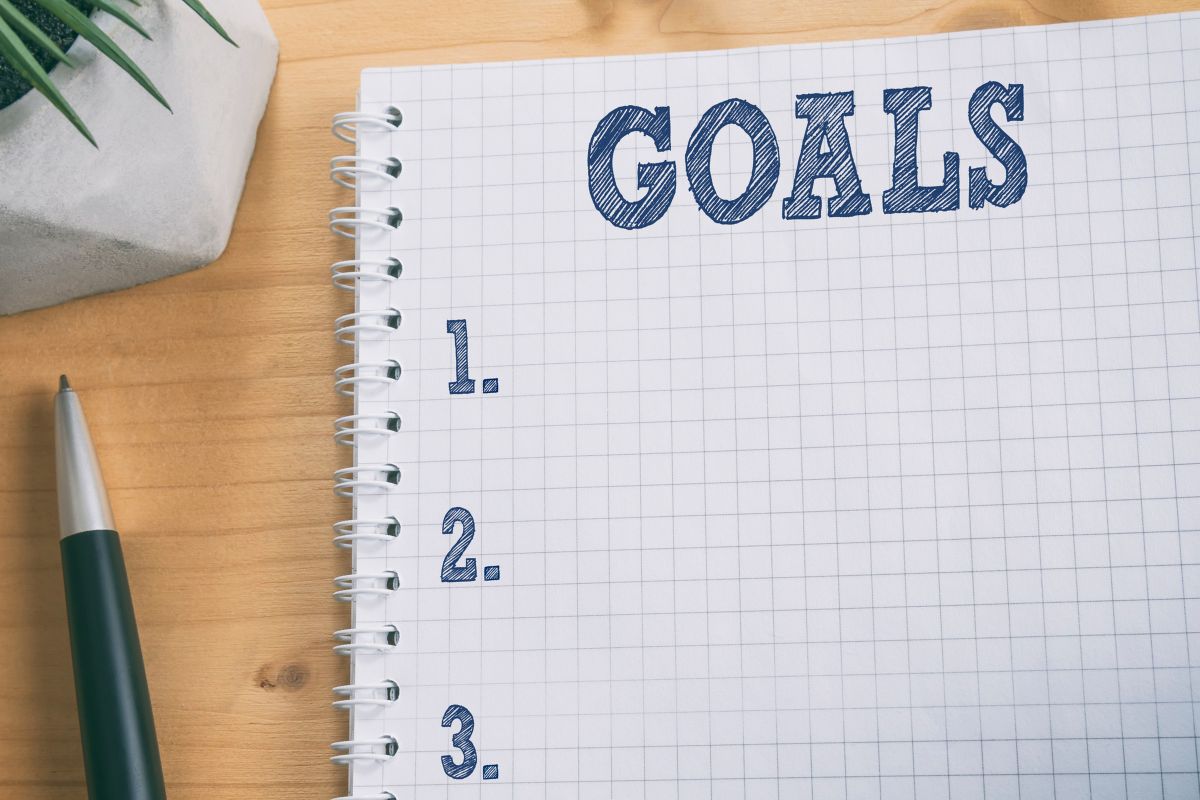 The image is about a pen and a notebook with goal lists.