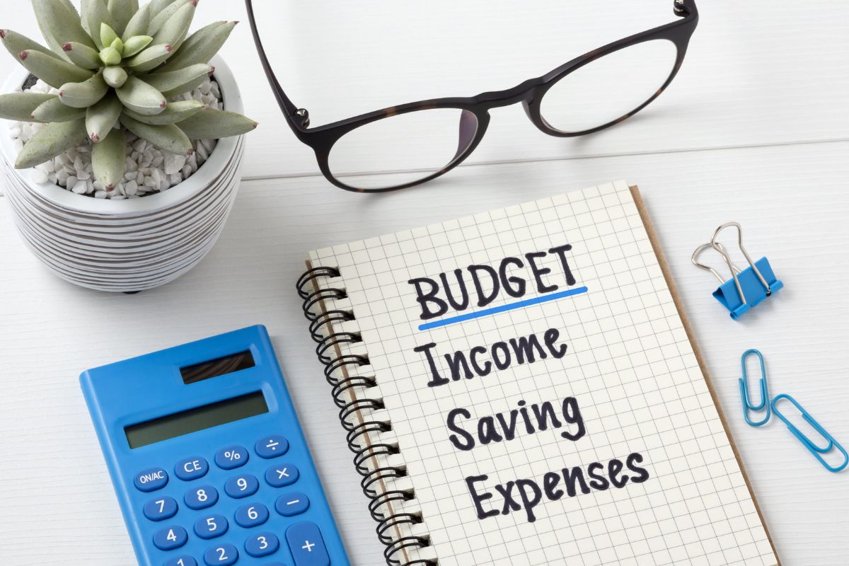 The photo of a calculator and a notebook with a budgeting plan.