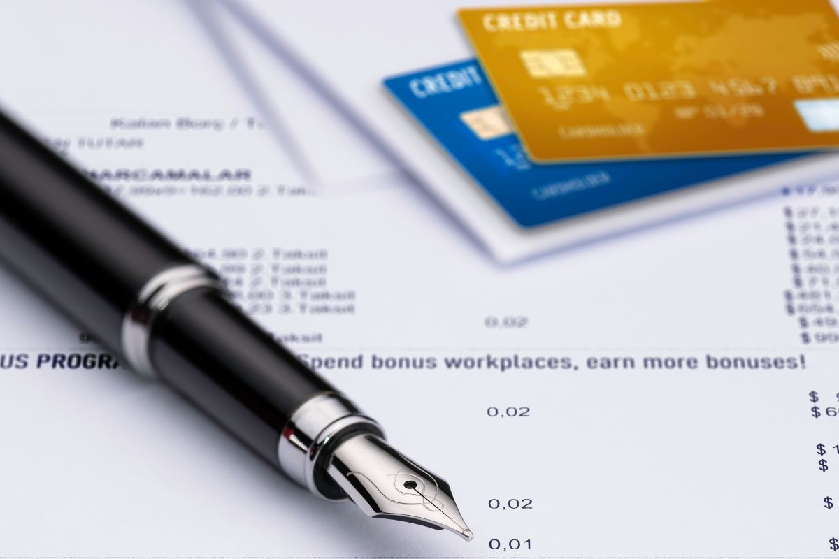 The picture is about papers, a pen, and a credit card balance.
