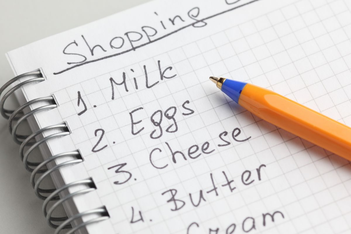 The picture shows a pen and a notebook with a shopping list.