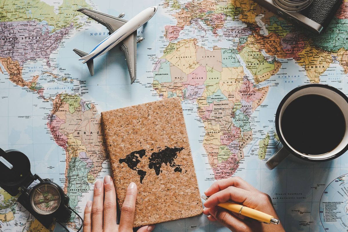 The image of the world map, a plant, and a woman's hand planning for financing wants.