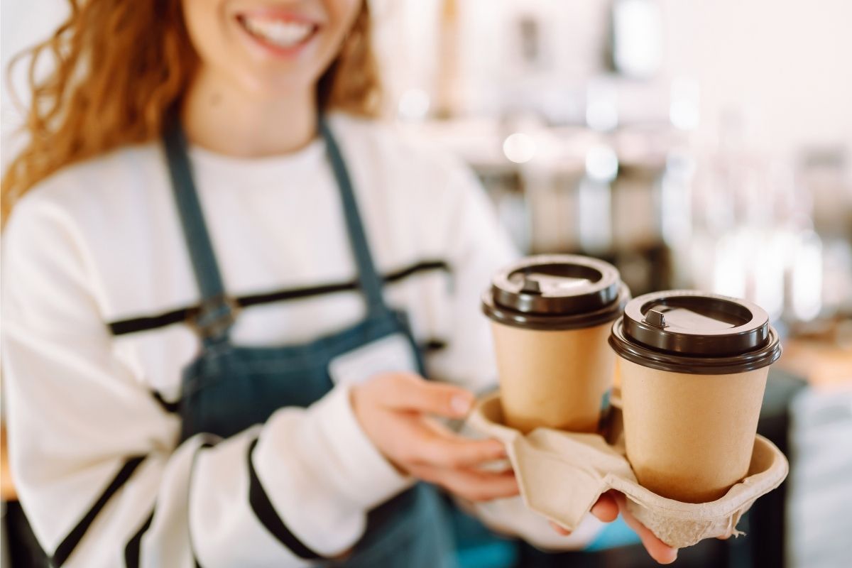 The photo is about a lady showing off two cups of coffee, which shows how small purchases pile up.