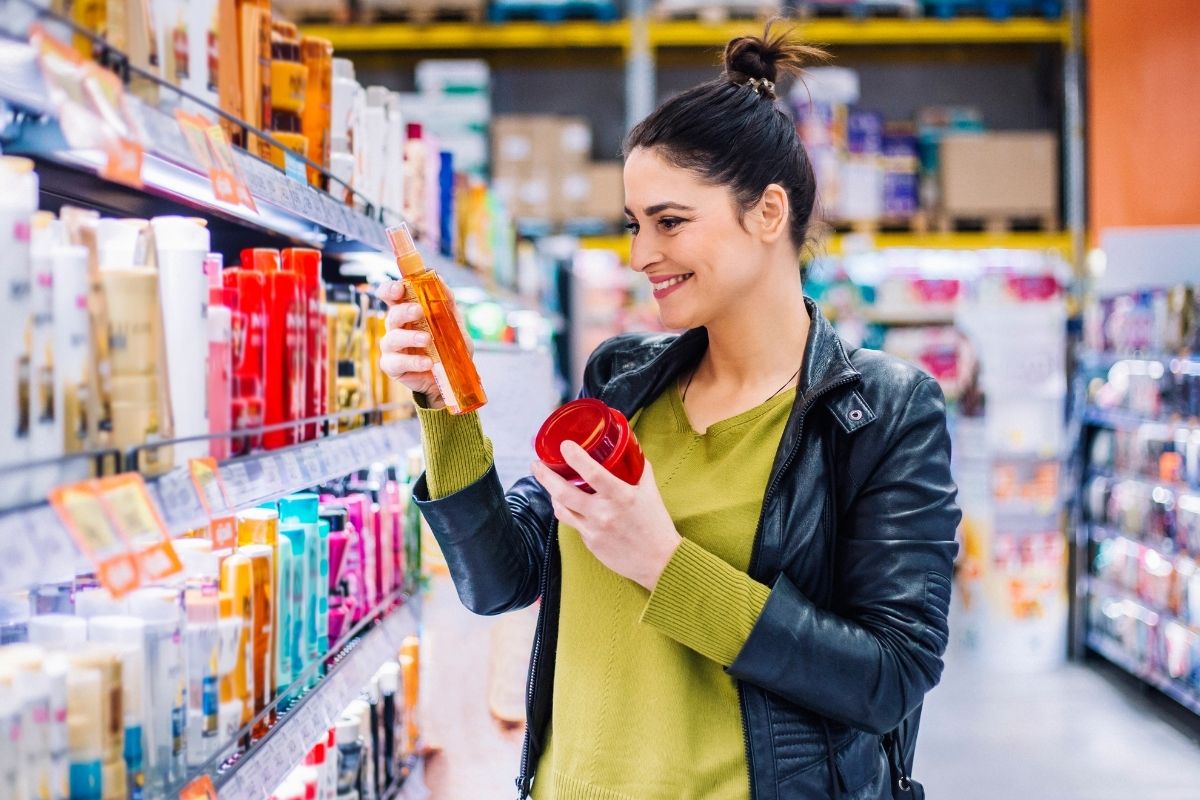 The image shows a woman comparing the price per unit of the products.