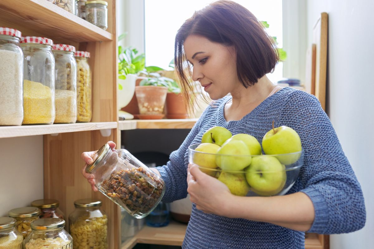 The picture is about a woman picking up ingredients from what's already in the pantry. 
