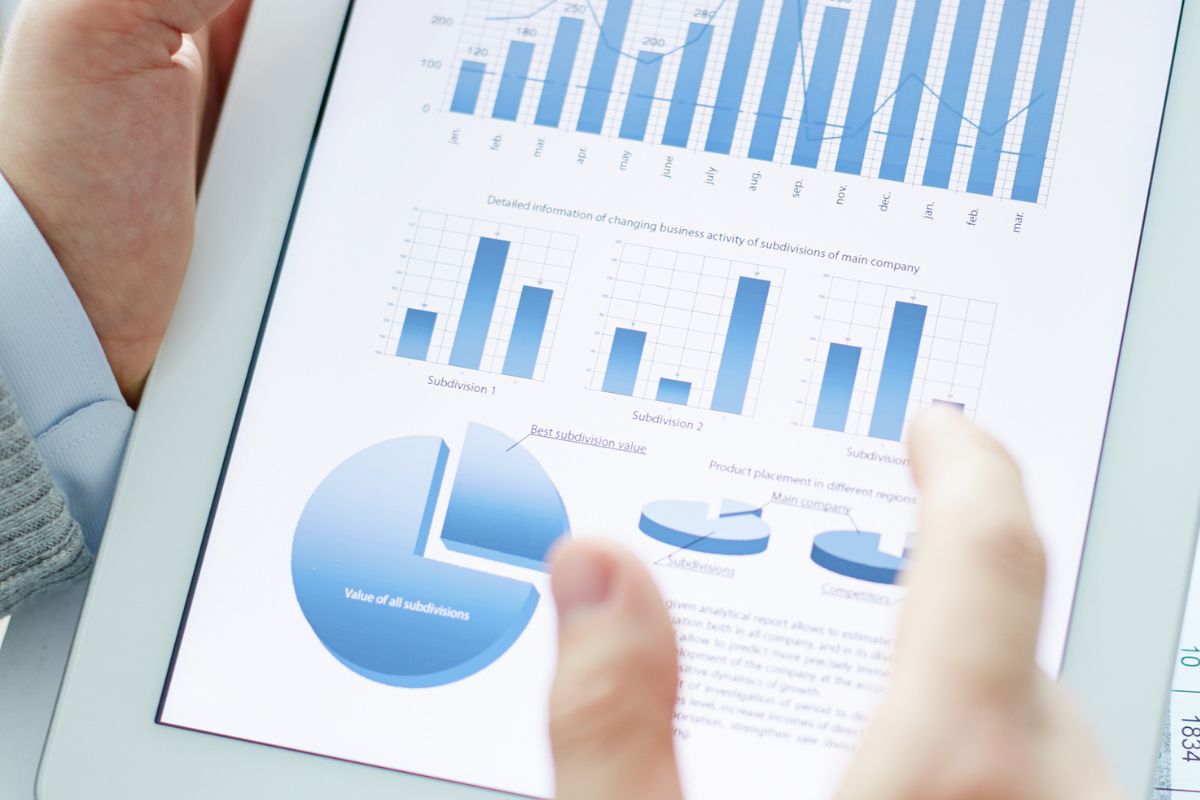 The image is about a man's hand using a tablet device for data analysis.