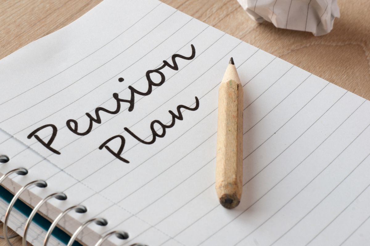 The photo shows a pen and a notebook with pension plan wording.