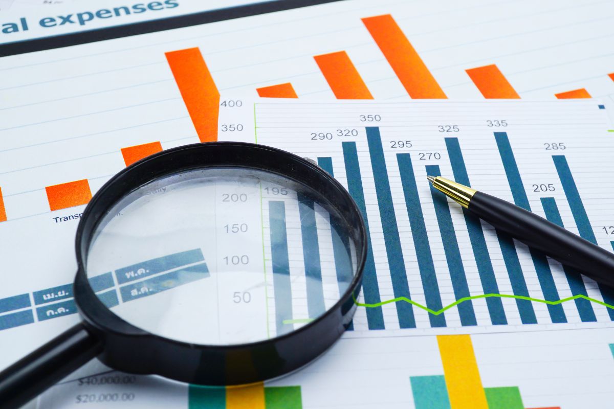 The photo is about papers, a magnifying glass, and a pen used for financial analysis.