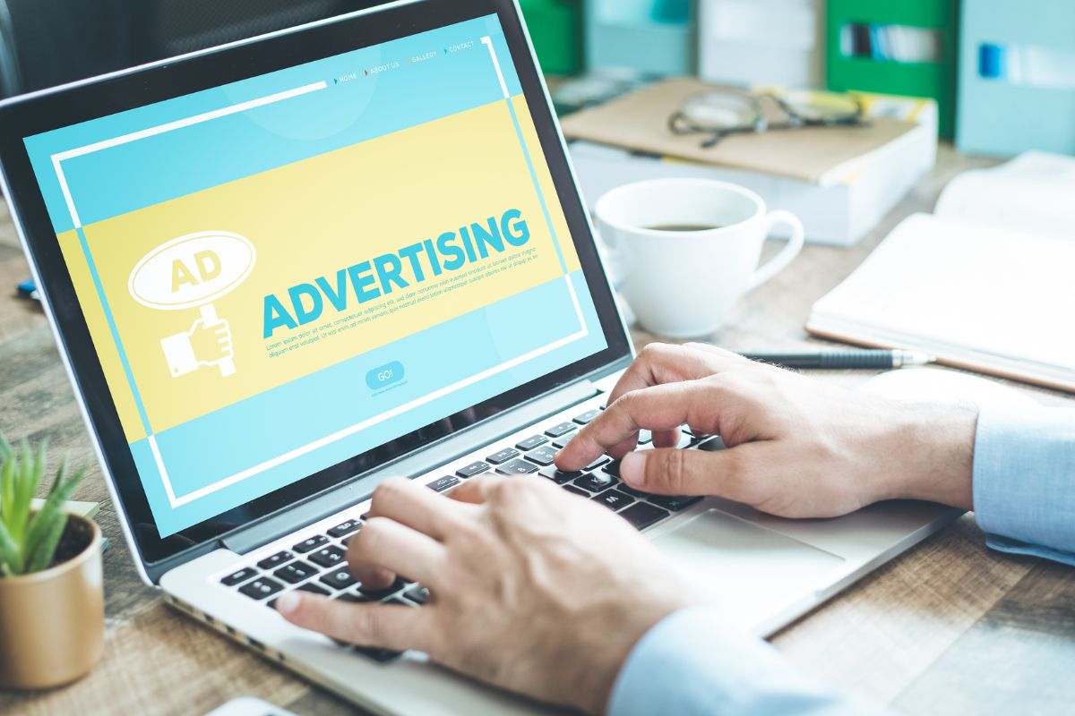 The photo is about a man's hand using a laptop for paid advertising work.