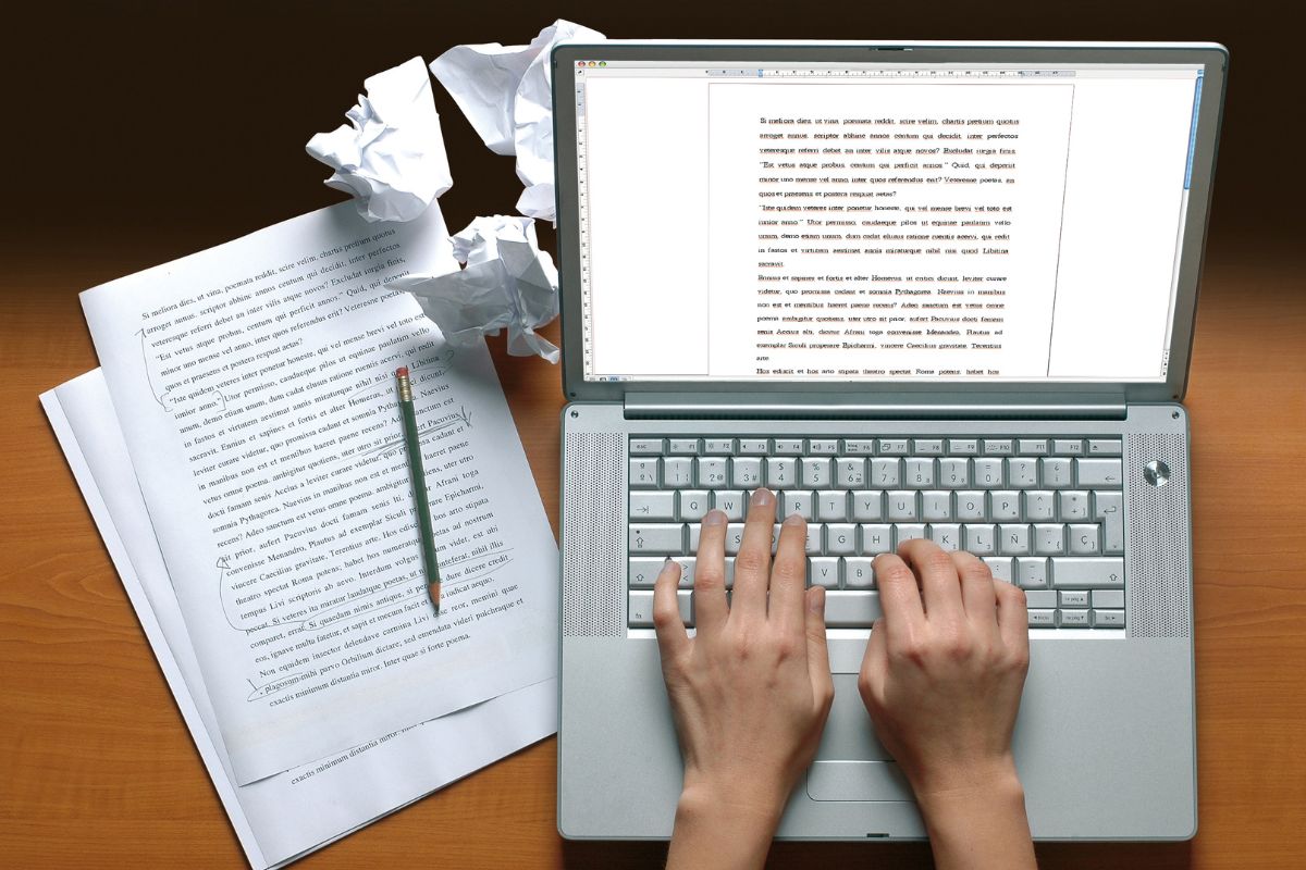 The picture is about papers and a lady's hand working as a freelance writer. 
