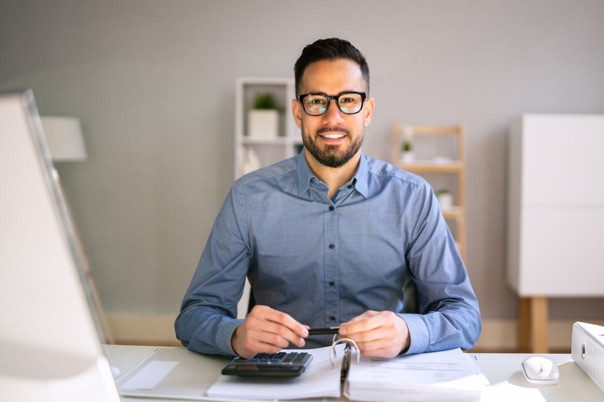 The image shows a man using a calculator, working as a remote bookkeeper.